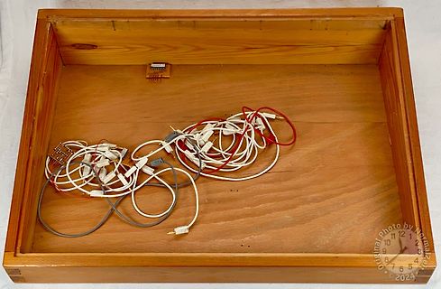 Diverse Kabel und eine kleine Platine in Holzkiste
