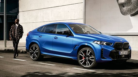 Blauer BMW SUV vor Gebäude mit Person
