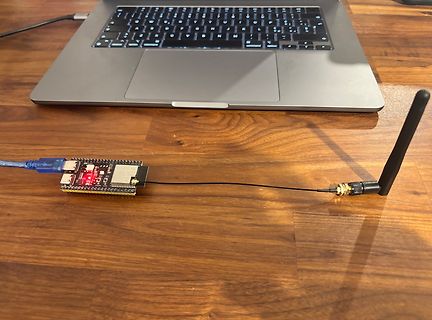 Mikrocontroller-Board mit Antenne und Laptop auf Holztisch
