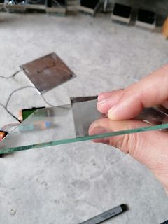 Hand hält eine Glasscheibe über einer Werkstattumgebung
