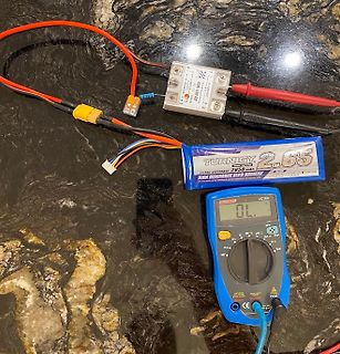 Multimeter, LiPo-Akku und Ladegerät auf Tisch