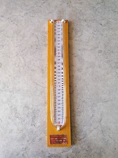 Vertikales Glasthermometer auf Holzbrett