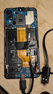 Offenes Smartphone mit freigelegter Elektronik und Flachbandkabel