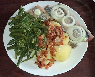 Teller mit Fisch, Kartoffeln, grünen Bohnen und Zwiebelringen