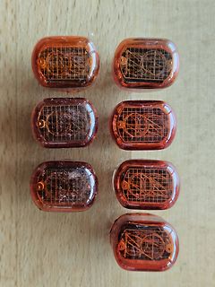 Sieben transparente orangefarbene Bauteile auf Holzuntergrund