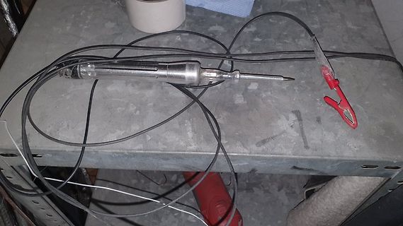 Lötkolben und Krokodilklemme auf Werkstattunterlage