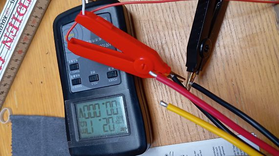 Digitalmultimeter mit Messklemmen auf Holztisch