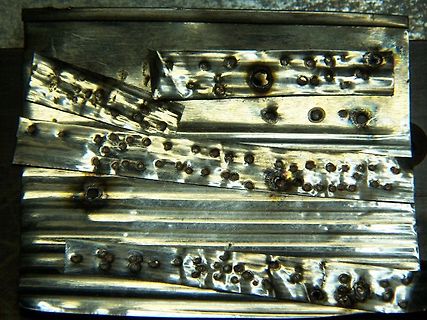 Beschädigte Metalloberfläche mit Löchern und Brandspuren