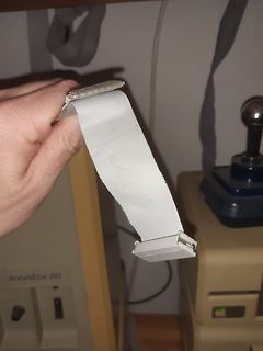 Hand hält Flachbandkabel vor altem Computer
