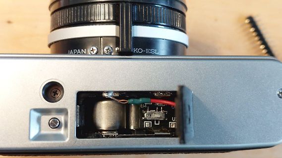 Geöffnetes Batteriefach einer Kamera mit Kabeln