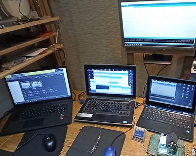 Arbeitsplatz mit drei Laptops und Monitor in einer Werkstatt