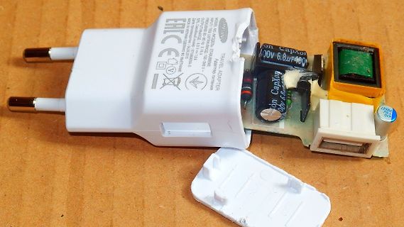 Geöffnetes Samsung Reiseadapter-Netzteil auf Holzuntergrund