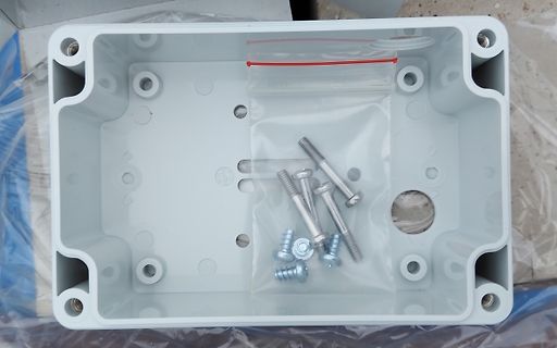 Leere Kunststoff-Gehäusebox mit Schrauben in Plastiktüte