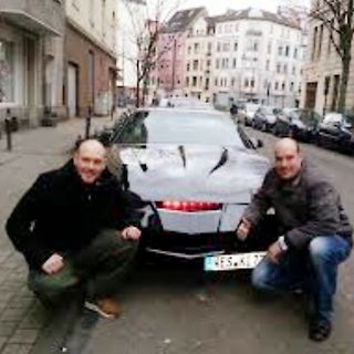 Zwei Männer vor einem Auto auf einer Straße
