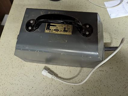Graues Metallgehäuse mit Typenschild und Tragegriff