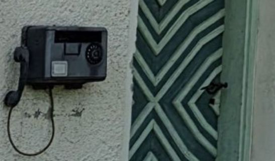 Altes Telefon an einer Wand neben einer Tür