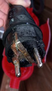 Beschädigter Netzstecker mit Brandspuren und Korrosion