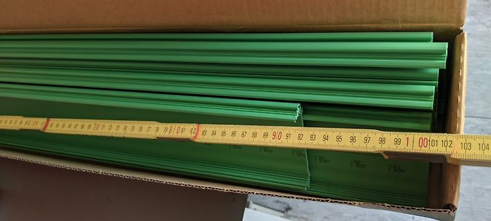 Grüne Profile in einem Karton mit Maßband