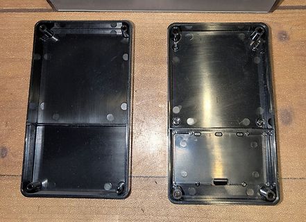Zwei schwarze Kunststoffgehäuse auf Holzuntergrund