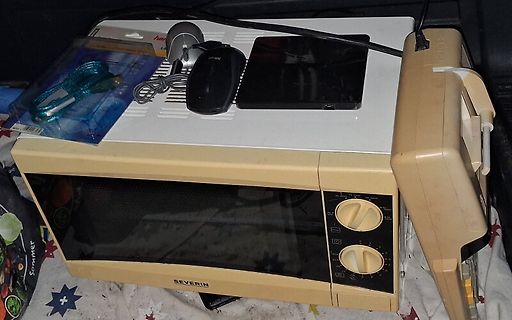 Mikrowelle mit Computermaus und Smartphone darauf