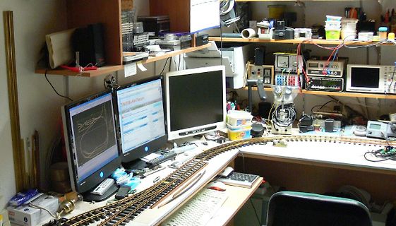 Werkstatt mit Monitoren, Oszilloskop und Modellbahnschienen