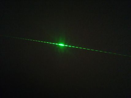 Grüner Laserstrahl im Dunkeln