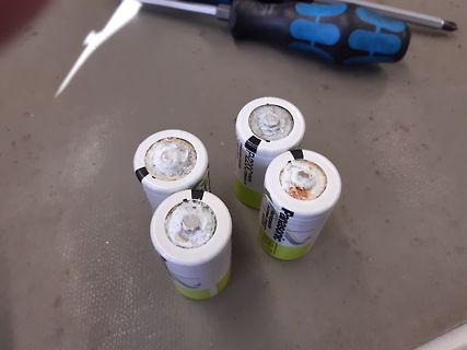 Vier ausgelaufene Batterien auf Tisch