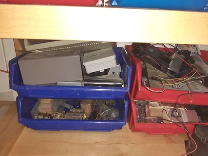 Elektronikbauteile und Gehäuseteile in blauen und roten Kunststoffboxen