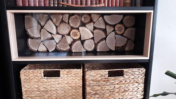 Holzscheite in einem Regal mit Weidenkörben
