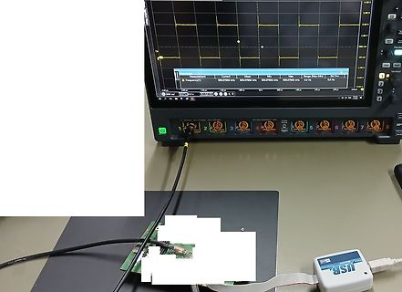 Abfotografiertes Oszilloskop mit Messwerten und Leiterplatte