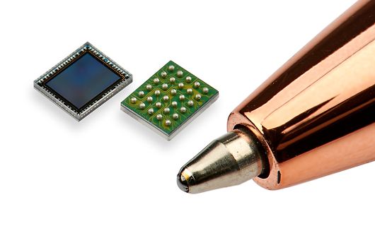 Mikrochip und Unterseite mit Lötpads neben Kugelschreiber