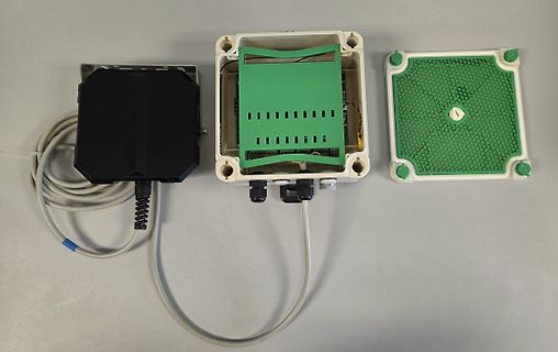 Geöffnetes Elektronikgehäuse mit Leiterplatte und Kabeln