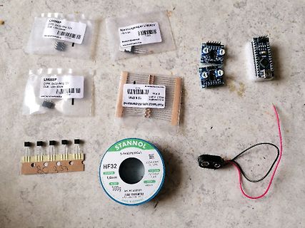 Elektronikbauteile und Lötzinn auf Werkstattuntergrund