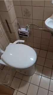 Toilette mit elektrischem Gerät an der Wand