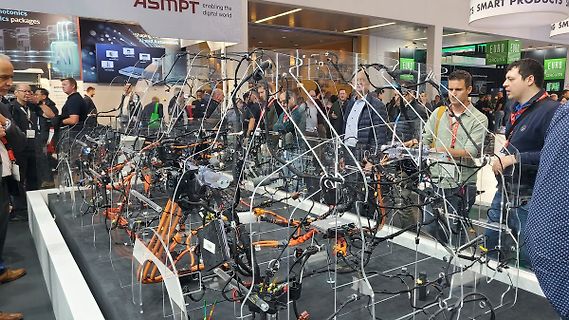 Menschen auf einer Messe vor Kabelbäumen