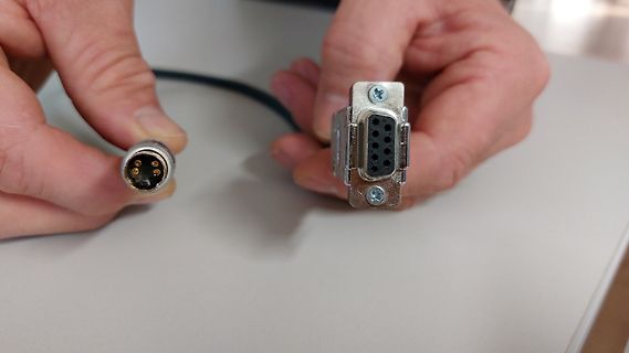 Hände halten zwei serielle Schnittstellenstecker