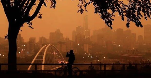 Silhouette einer Person mit Fahrrad vor Stadtpanorama bei Dunst