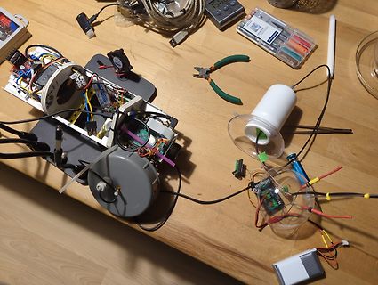 Elektronik-Prototyp mit Kabeln, Werkzeug und Bauteilen auf Holztisch