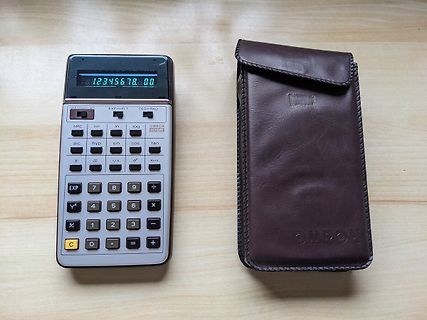 Taschenrechner und Lederetui auf Holztisch