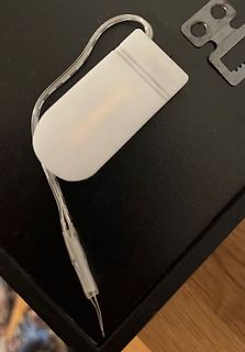 Weißes Kunststoffgehäuse mit Kabel und Metallhalterung