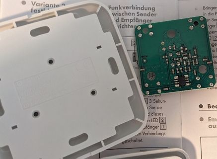 Geöffnetes Gehäuse und grüne Leiterplatte auf Anleitung