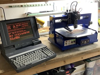 Laptop und CNC-Maschine auf Werkstattarbeitstisch