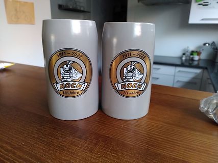 Zwei graue Becher mit Jubiläumslogo