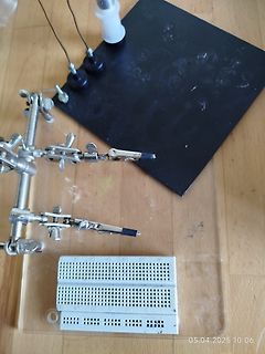 Elektronik-Aufbau mit Breadboard, Krokodilklemmen und schwarzer Platte