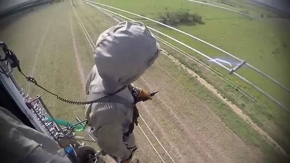Person in Schutzkleidung bei Arbeiten an Hochspannungsleitungen