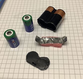 Batterien, Batteriefach und Klebeband auf Millimeterpapier