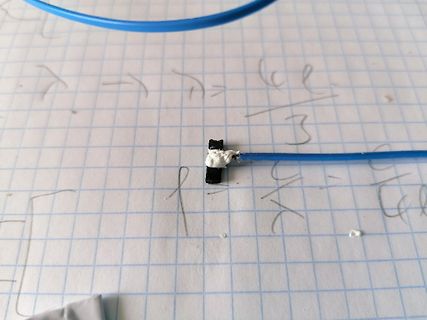 Blaues Kabel auf kariertem Papier mit handschriftlichen Formeln