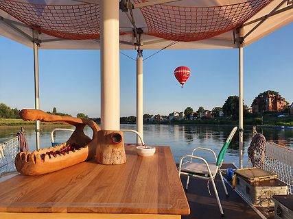 Holztisch auf Boot mit Blick auf Fluss und Heißluftballon