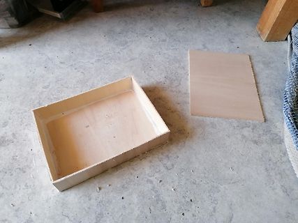 Holzschachtel und Holzplatte auf Betonboden