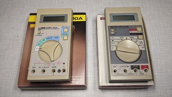 Zwei digitale Multimeter auf Karton